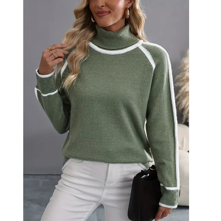 Woman wearing sage green turtleneck sweater with white trim, white pants, Rovelli fashion