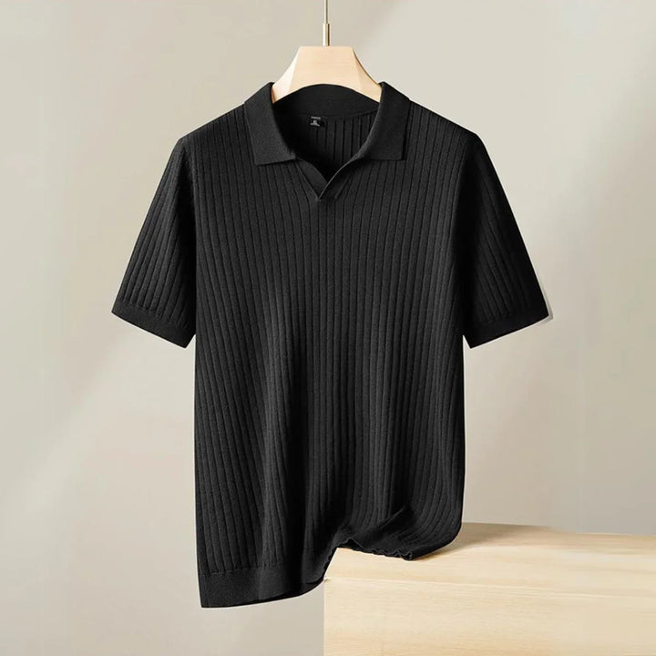 A short-sleeved, black ribbed knit polo shirt with a subtle vertical pattern is displayed on a wooden hanger against a neutral background—perfect for the urban professional seeking effortless style.