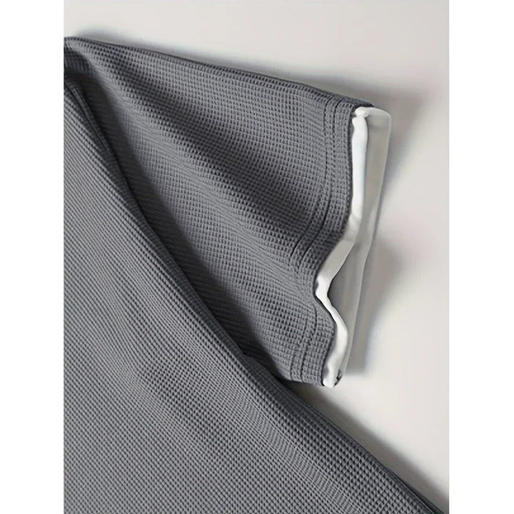 Rovelli grey waffle textured blanket with white lining, neatly folded on a white surface