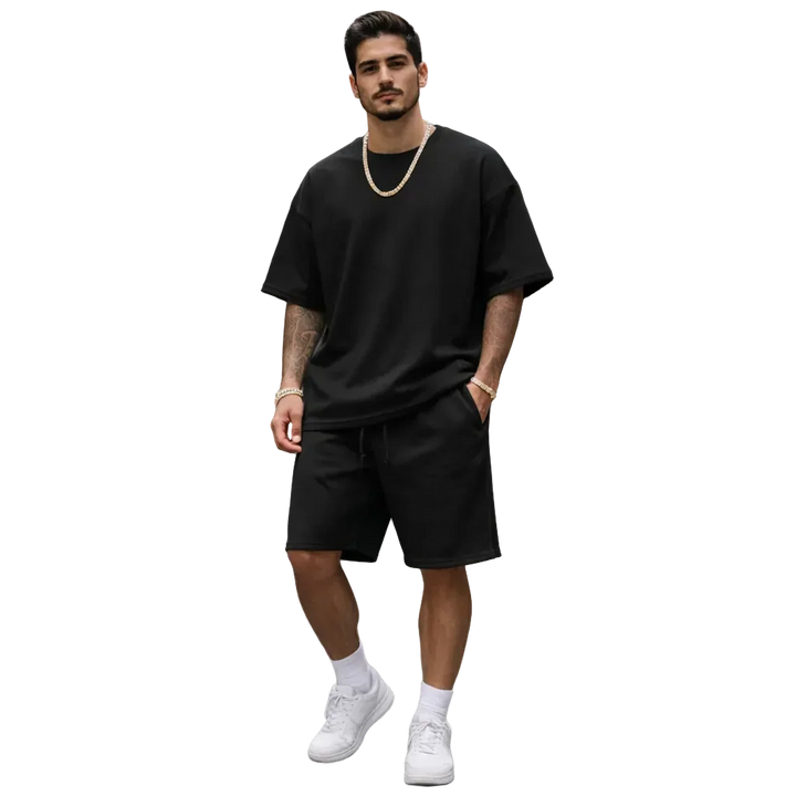 Man wearing black oversized t-shirt and shorts set with gold chain, white sneakers, Rovelli style