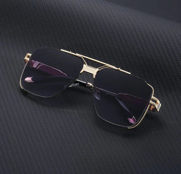 A pair of stylish, gold-rimmed vintage sunglasses with dark lenses and UV400 protection is placed on a textured black surface.