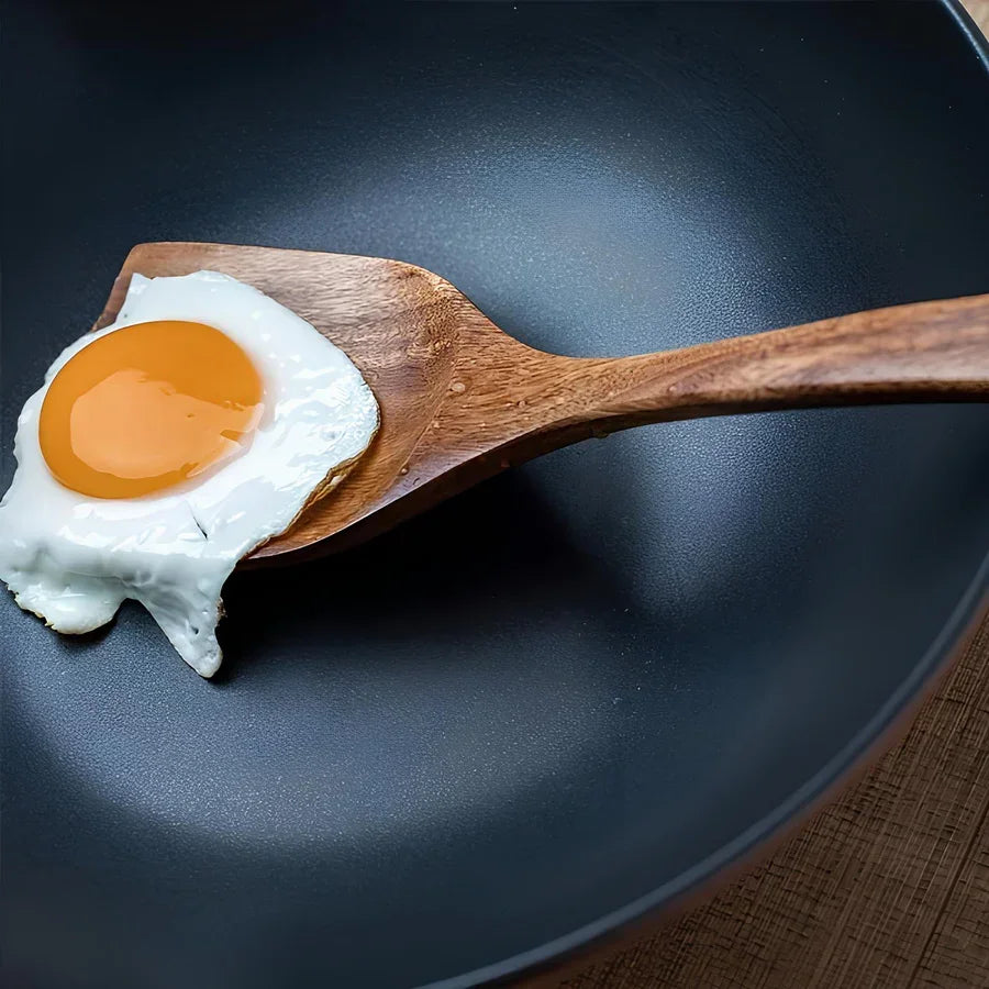 Wooden spatula lifting fried egg in non-stick pan, Rovelli kitchen accessories