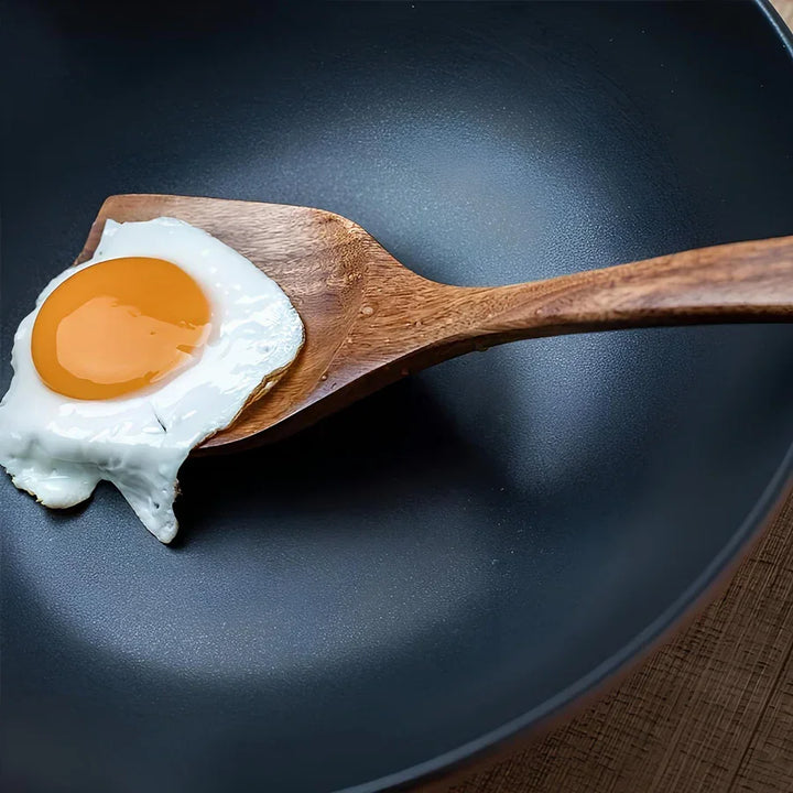 Wooden spatula lifting fried egg in non-stick pan, Rovelli kitchen accessories