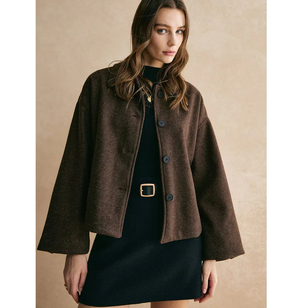 Woman in brown button-up jacket and black dress with gold belt, Rovelli fashion
