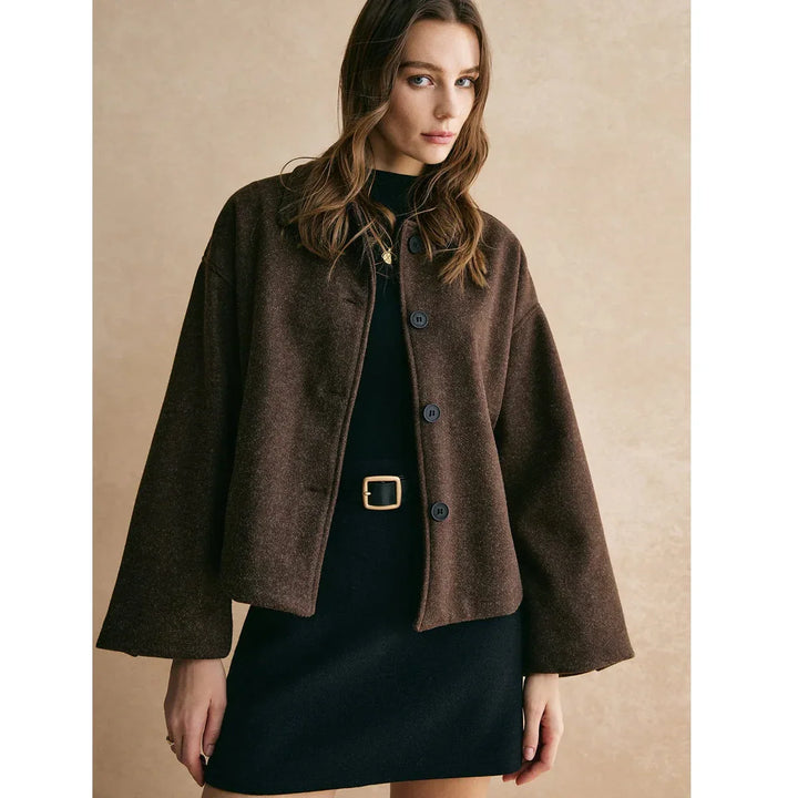 Woman in brown button-up jacket and black dress with gold belt, Rovelli fashion