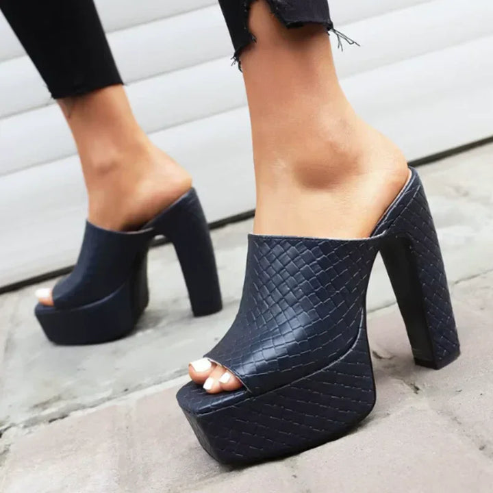 Dark blue woven leather platform sandals with chunky high heels by Rovelli, worn outdoors.