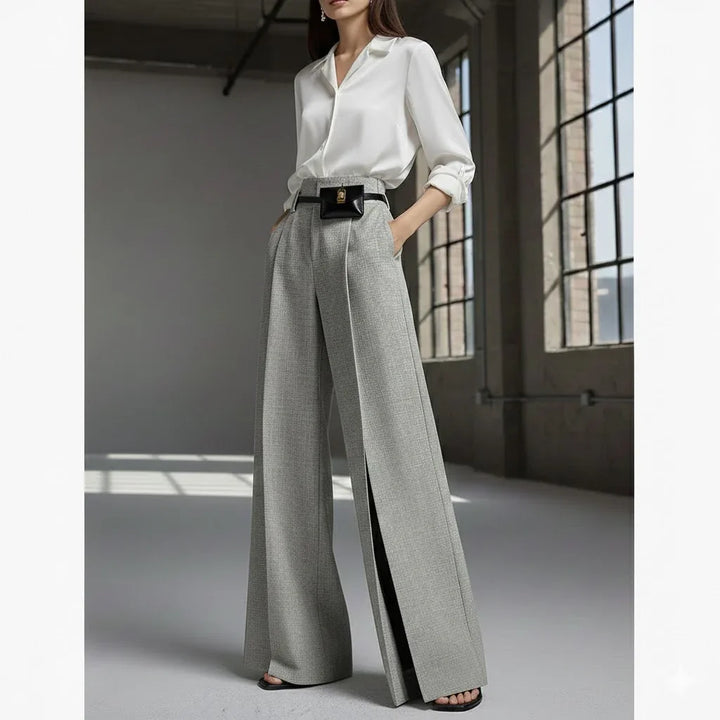 Woman in Rovelli Bryle pleated split trousers and white blouse in modern loft