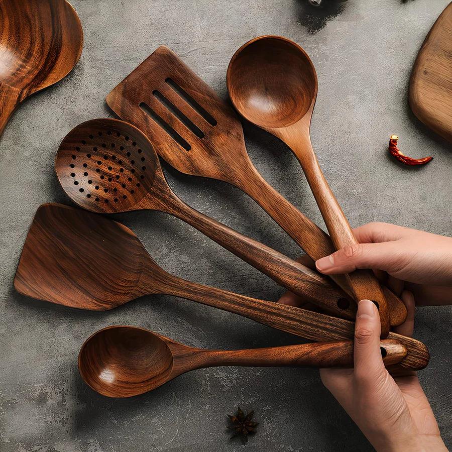 Set of five natural teak wooden kitchen utensils held in hands on a grey surface, Rovelli