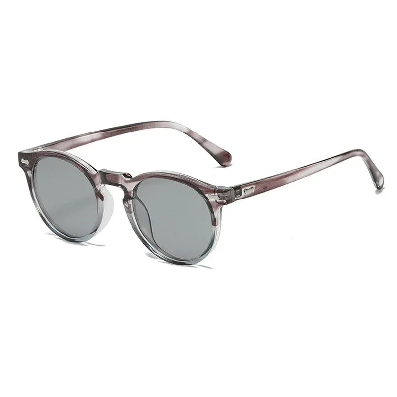 Round frame sunglasses with transparent gray frames and dark tinted lenses, offering UV400 protection, displayed on a white background at an angle showing both the front and side of the glasses.