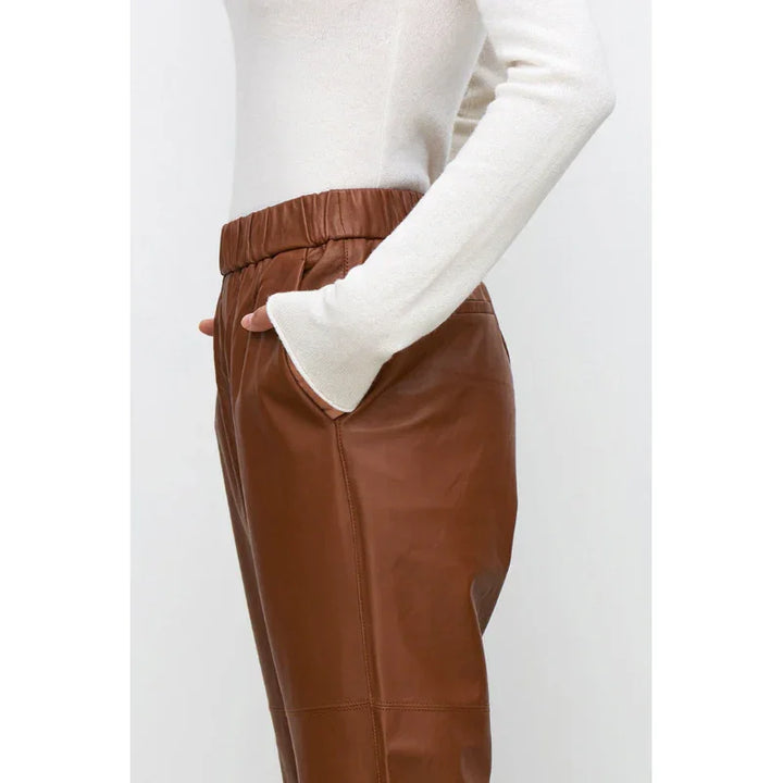 Woman wearing Rovelli brown genuine leather pants with white sweater