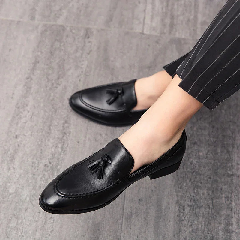 A person wearing mens loafers crafted from genuine leather and pinstripe pants, standing on a grey tiled floor.