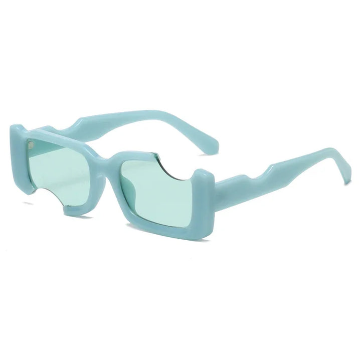 Light blue rectangular sunglasses with thick geometric frames and green-tinted lenses. Angular, wavy cutouts along the top edges and arms create a distinctive, futuristic design perfect for bold street style looks.