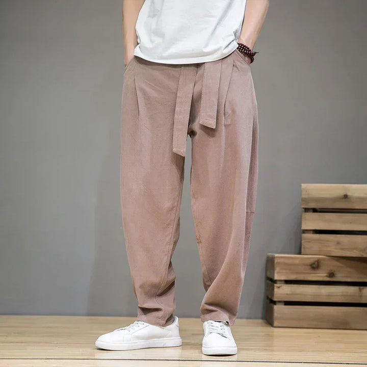 Rovelli men's beige relaxed fit pants with tie waist, casual white sneakers, indoor setting