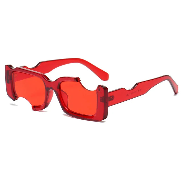 Avant-garde sunglasses in bright red feature thick, rectangular frames with geometric cut-out details and a slight curve to the arms. These irregular sunglasses offer bold style against a white backdrop.