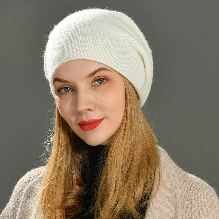 Woman wearing a soft white knit beanie, neutral sweater, and red lipstick, Rovelli fashion