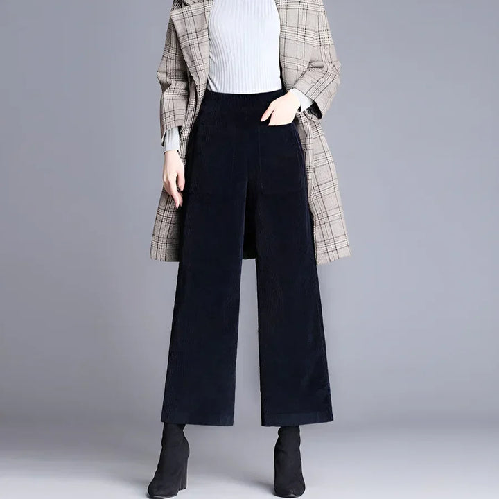 Woman wearing wide-leg black corduroy pants, plaid coat, and black boots from Rovelli
