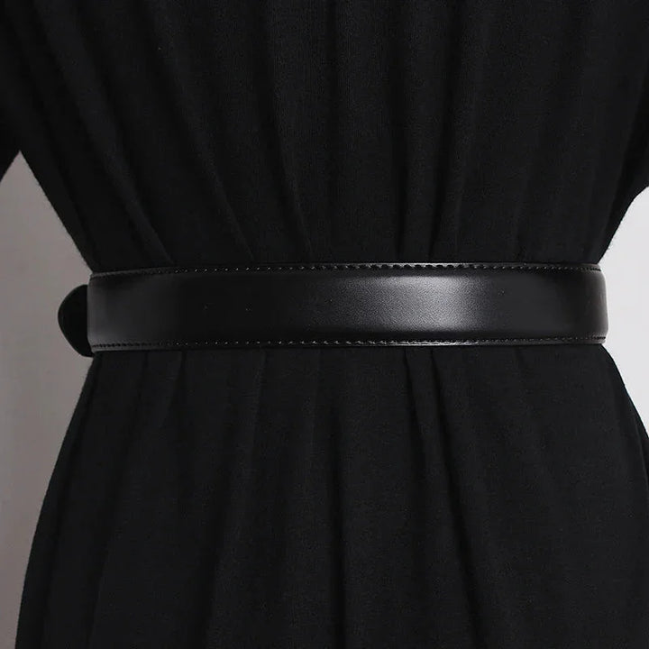A close-up of a person wearing a black outfit with a wide, smooth genuine leather belt cinched around the waist. The material appears soft and the belt has a subtle stitched edge.
