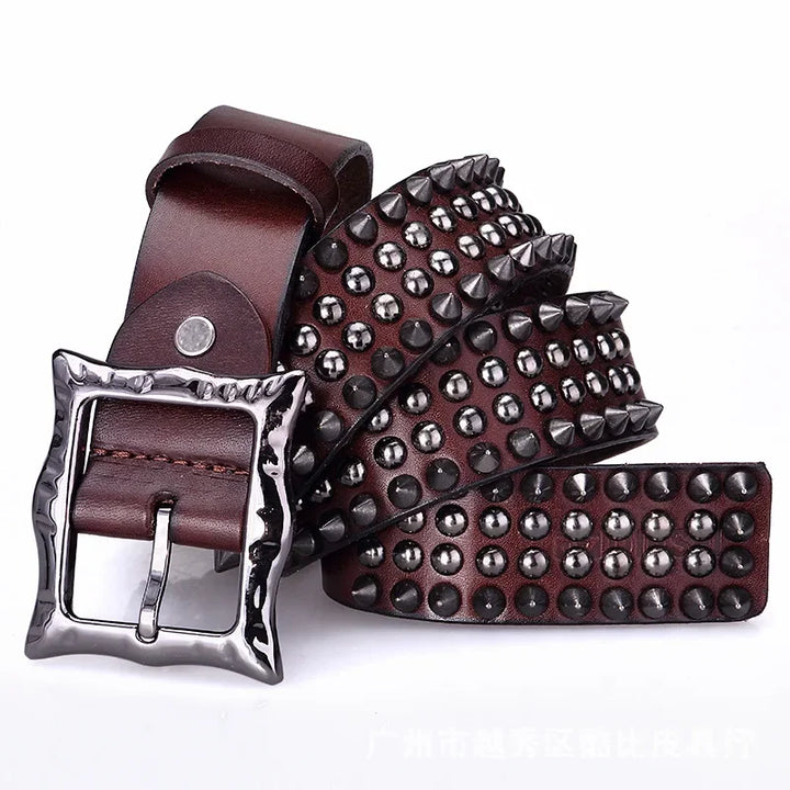 A brown leather belt with a large, shiny silver adjustable buckle. The belt features multiple rows of round and cone-shaped studs, showcasing bold studded detailing along its length.