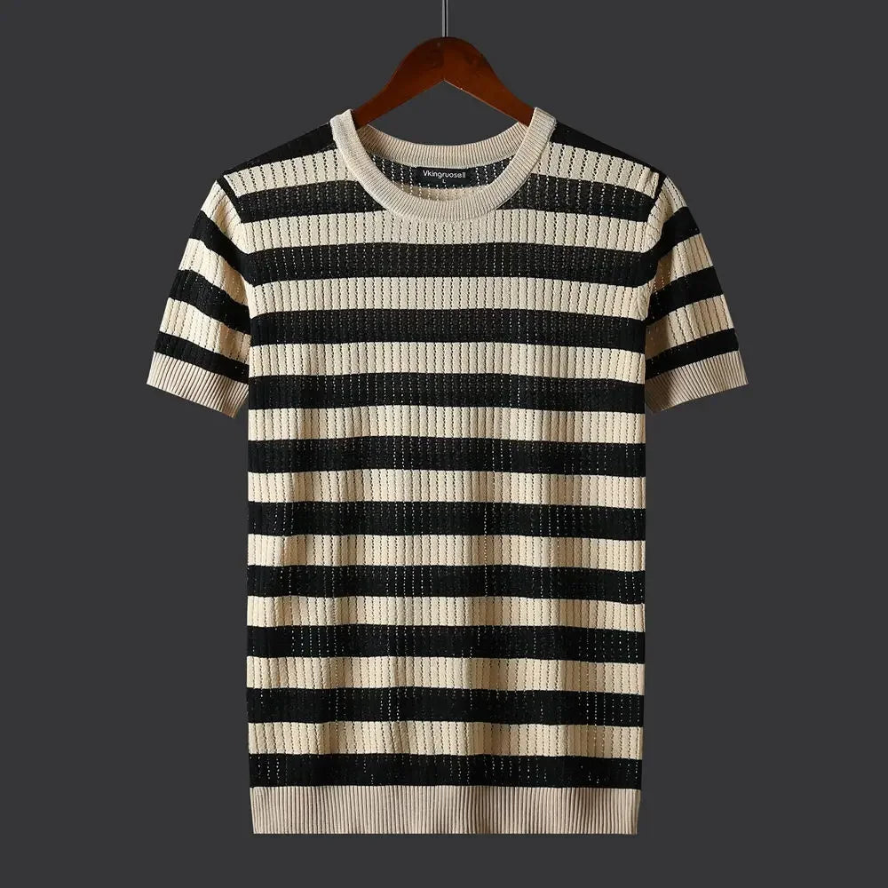 A short-sleeved knit sweater with black and beige horizontal stripes and a subtle ribbed texture, displayed on a wooden hanger against a dark gray background.