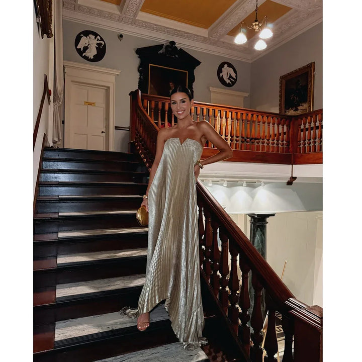 Woman in elegant gold strapless gown on staircase, Rovelli fashion, formal event setting