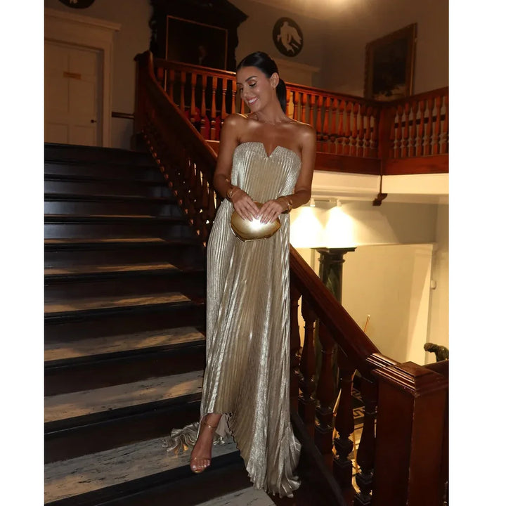 Woman in a metallic gold strapless dress holding a clutch on a grand staircase, Rovelli fashion
