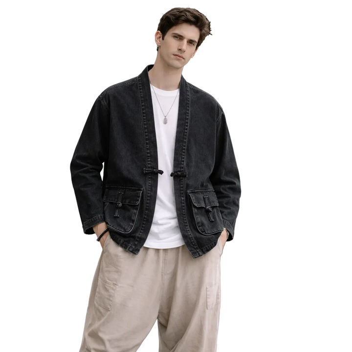 Man wearing Rovelli black kimono jacket with white shirt and beige pants on black background.