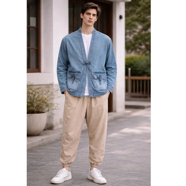 Man wearing light blue kimono denim jacket by Rovelli, beige pants, and white sneakers outdoors