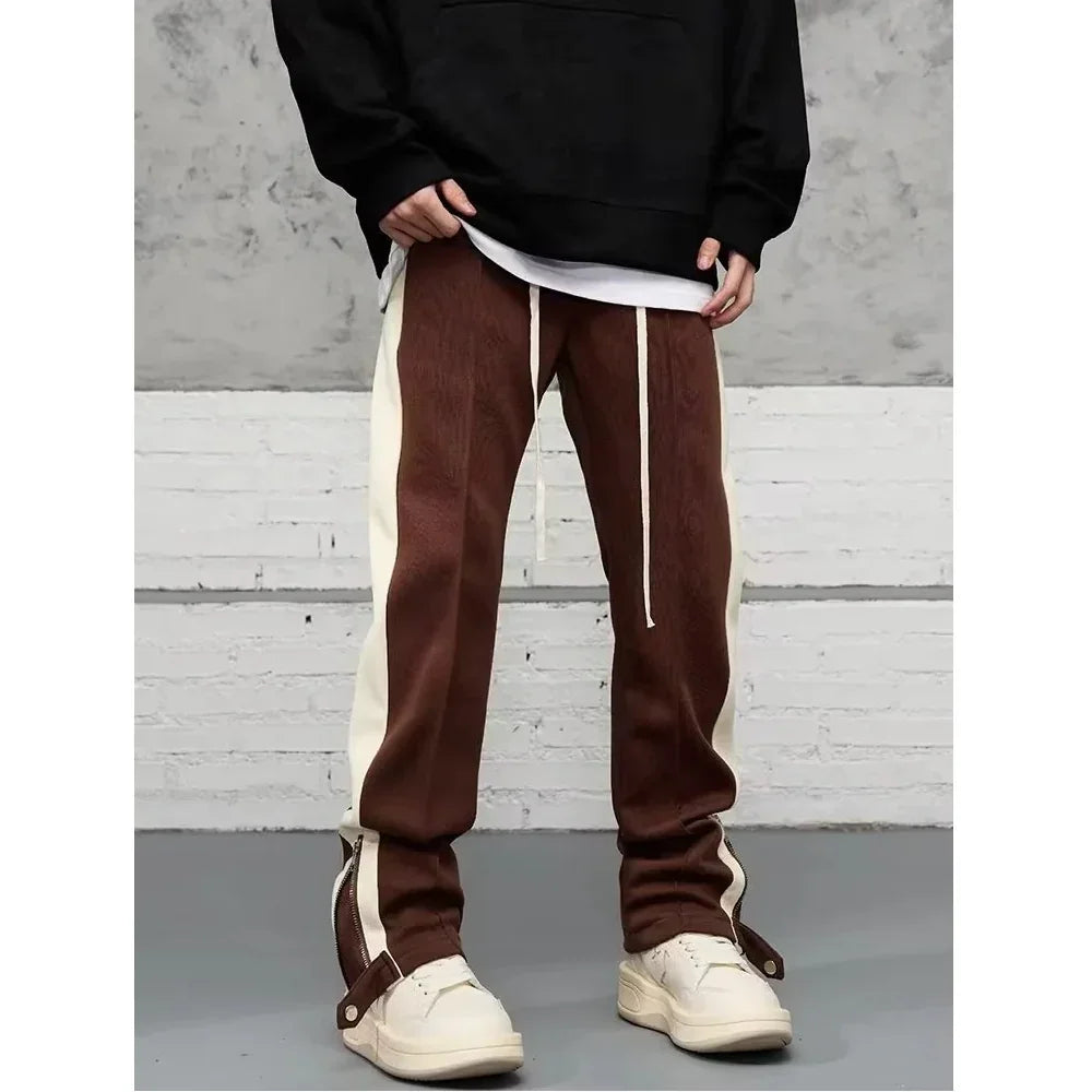 Men's brown and white streetwear track pants with side stripes, styled with sneakers by Rovelli