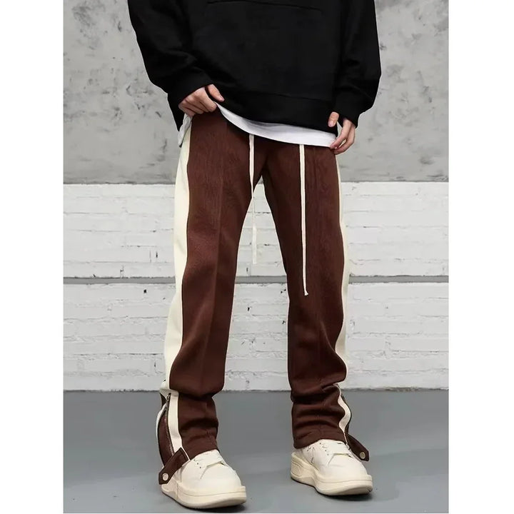 Men's brown and white streetwear track pants with side stripes, styled with sneakers by Rovelli