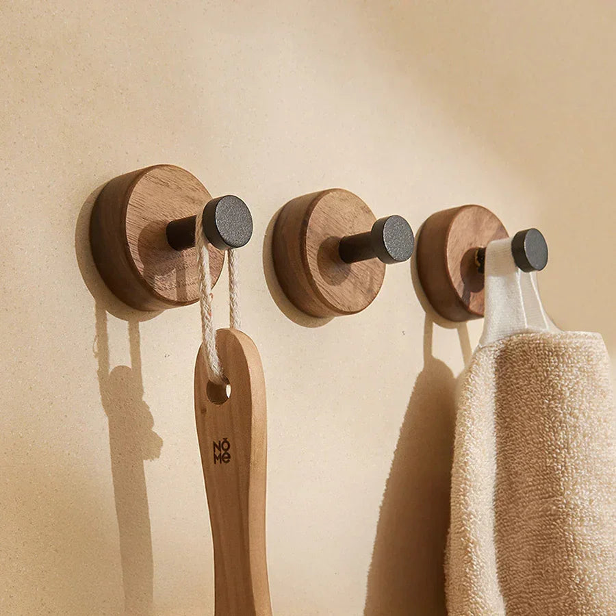 Rovelli wooden wall hooks with dark pegs, holding a brush and towel on beige wall