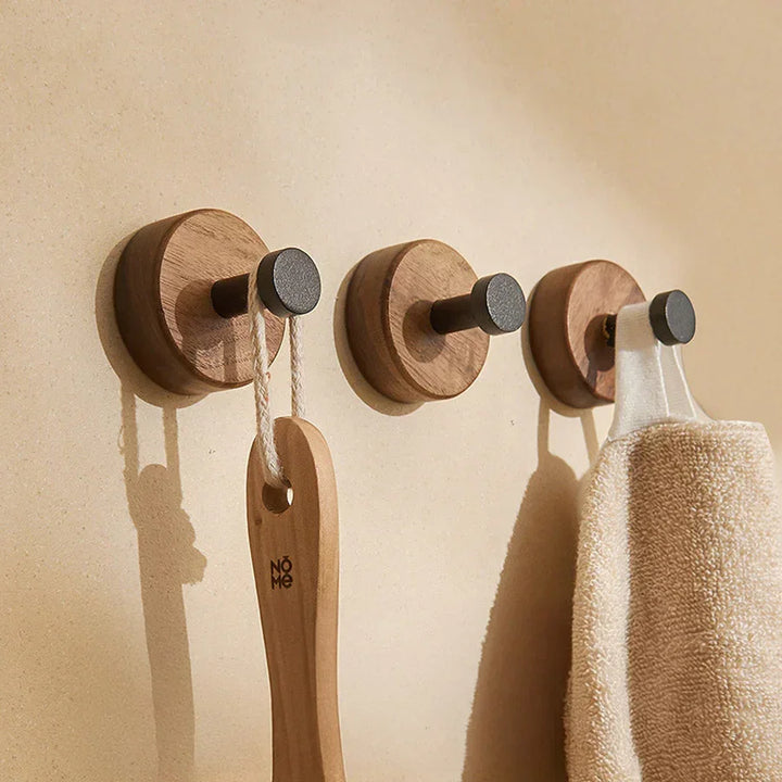 Rovelli wooden wall hooks with dark pegs, holding a brush and towel on beige wall