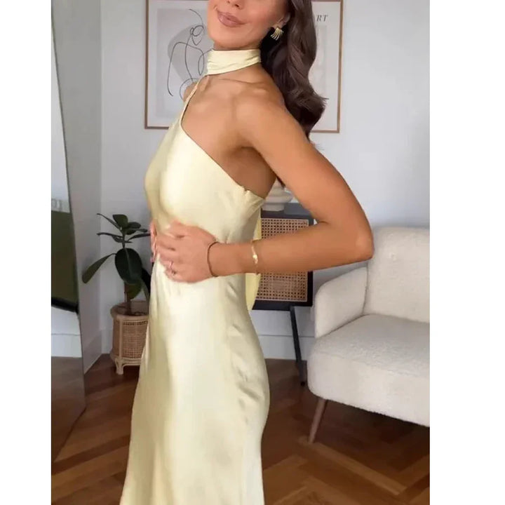 Woman in elegant yellow satin halter dress posing in modern living room, Rovelli fashion