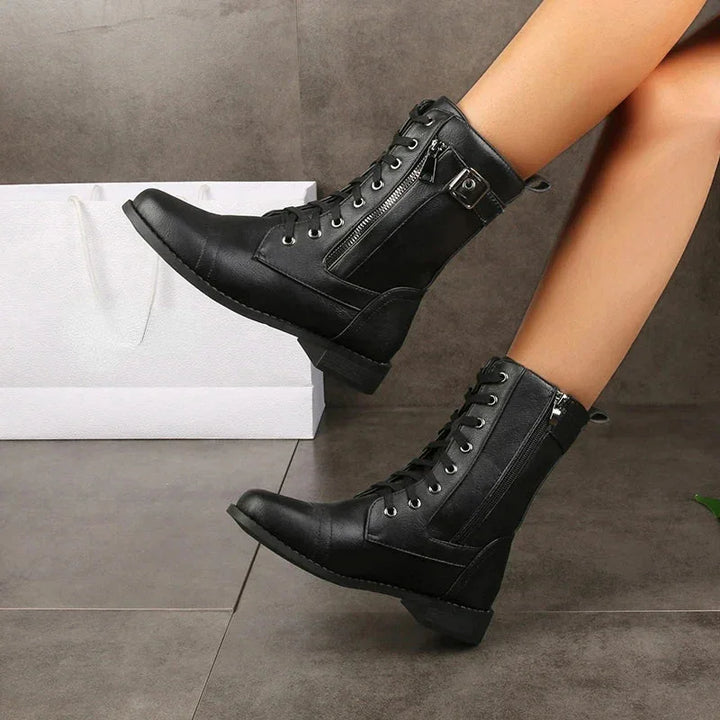 Rovelli black lace-up combat boots with zippers, worn indoors, near a white shopping bag.