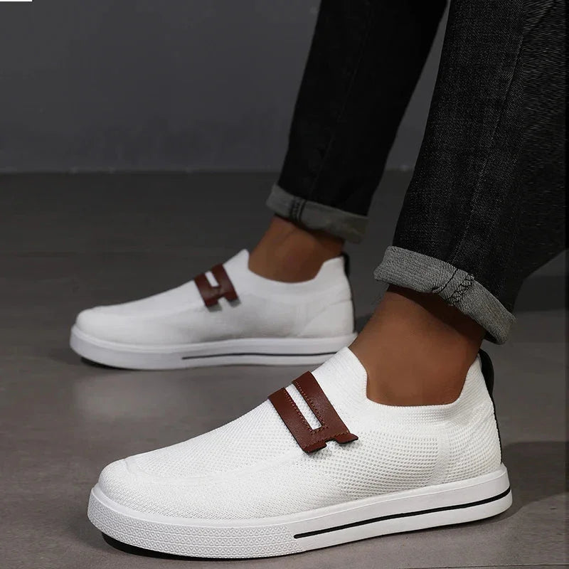 Rovelli white slip-on sneakers with brown accent, worn with rolled black jeans
