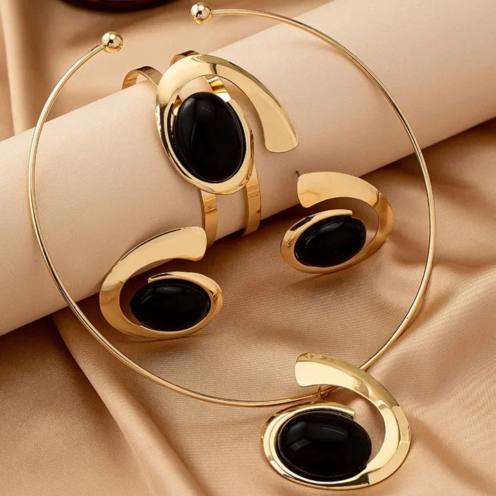 Rovelli gold jewelry set with black stone, including necklace, bracelet, earrings on satin fabric