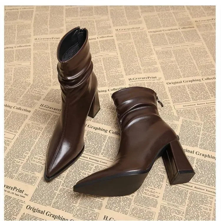 Rovelli brown heeled ankle boots with pointed toe, displayed on newspaper print background