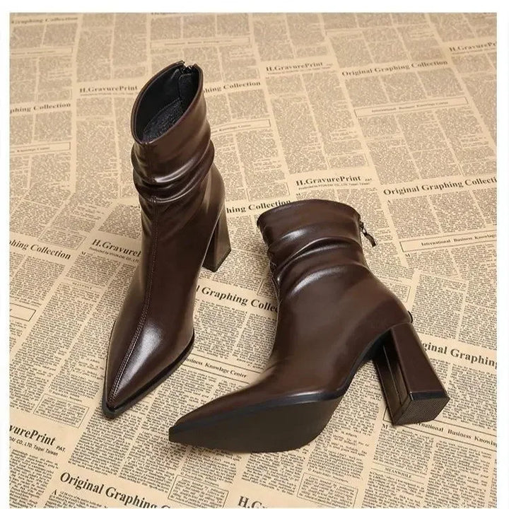Rovelli brown heeled ankle boots with pointed toe, displayed on newspaper print background