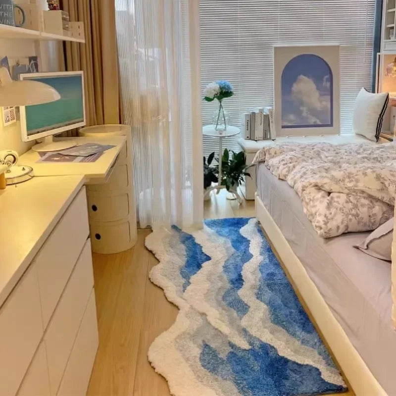 Modern bedroom with blue wave pattern rug, desk setup, and airy decor by Rovelli.