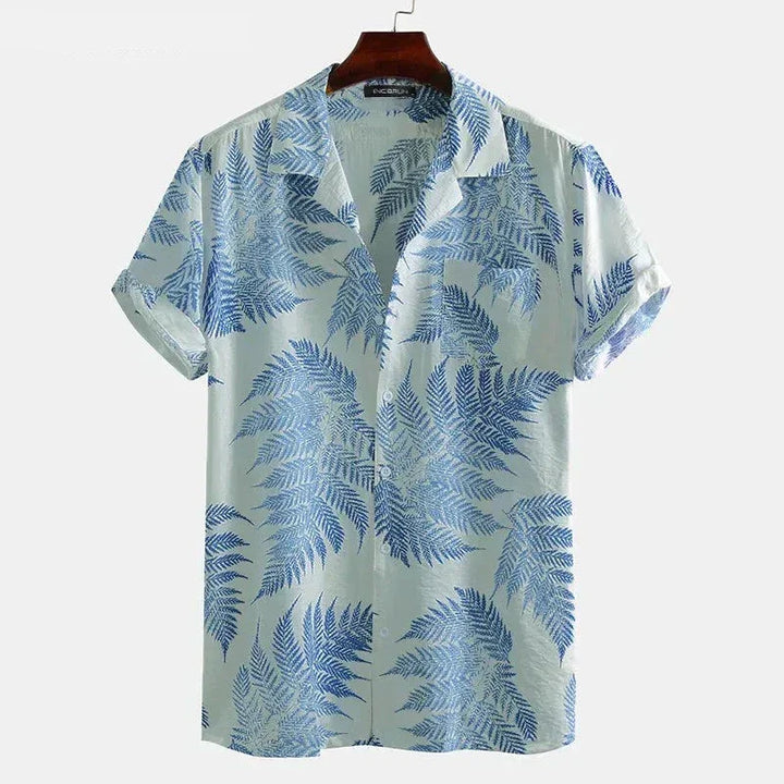A light blue cotton shirt with short sleeves and a classic design, featuring blue fern leaves. This button-up collared shirt is displayed on a wooden hanger against a plain white background—perfect for a casual brunch.