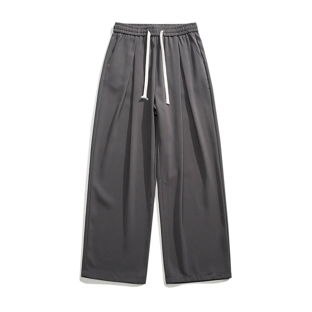 Wide-leg, charcoal gray GOAT Joggers with an elastic waistband and white drawstrings, displayed flat on a white background. These streetwear joggers feature side pockets, a relaxed fit, and effortlessly combine comfort with style.