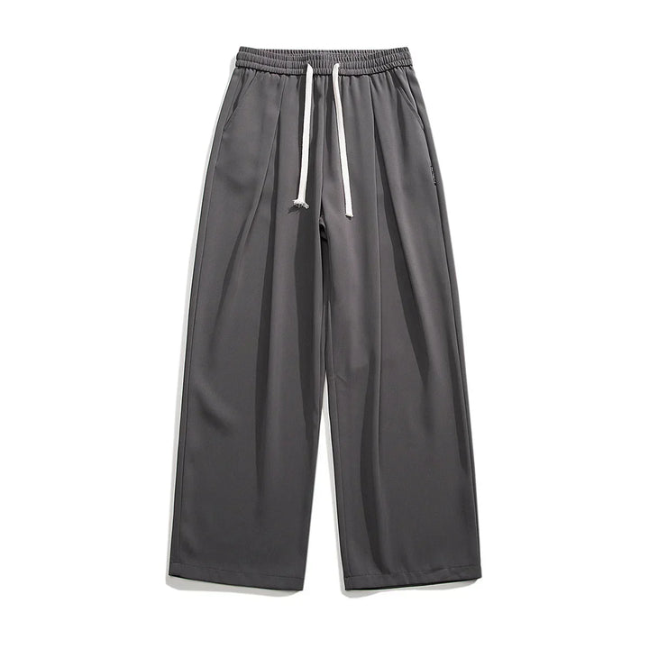 Wide-leg, charcoal gray GOAT Joggers with an elastic waistband and white drawstrings, displayed flat on a white background. These streetwear joggers feature side pockets, a relaxed fit, and effortlessly combine comfort with style.