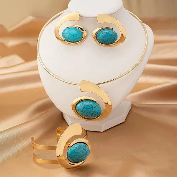 Gold and turquoise Rovelli jewelry set with necklace, earrings, and bracelet on satin fabric