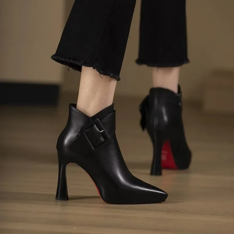 Rovelli pointed-toe black leather ankle boots with buckle and high heel on wooden floor