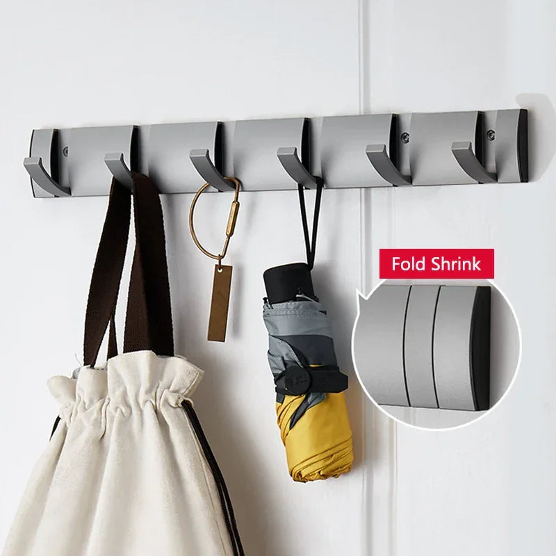 Wall-mounted foldable coat rack with hooks holding a bag, umbrella, and keychain by Rovelli
