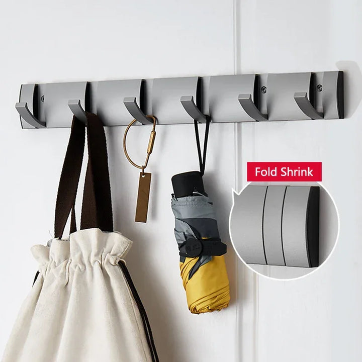 Wall-mounted foldable coat rack with hooks holding a bag, umbrella, and keychain by Rovelli