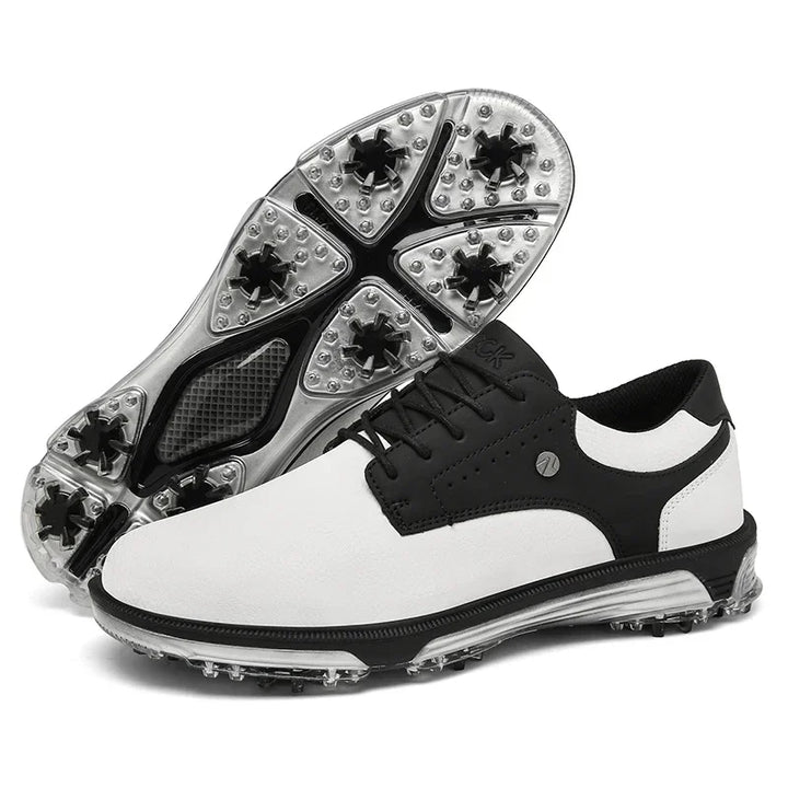 A pair of black and white golf shoes with spiked, translucent soles. One shoe is upright, displaying the upper design and reinforced toe cap, while the other is flipped to show the detailed tread and high-traction outsole.