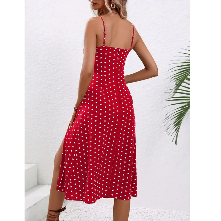 Woman in red polka dot sundress standing outdoors near white textured wall, Rovelli fashion