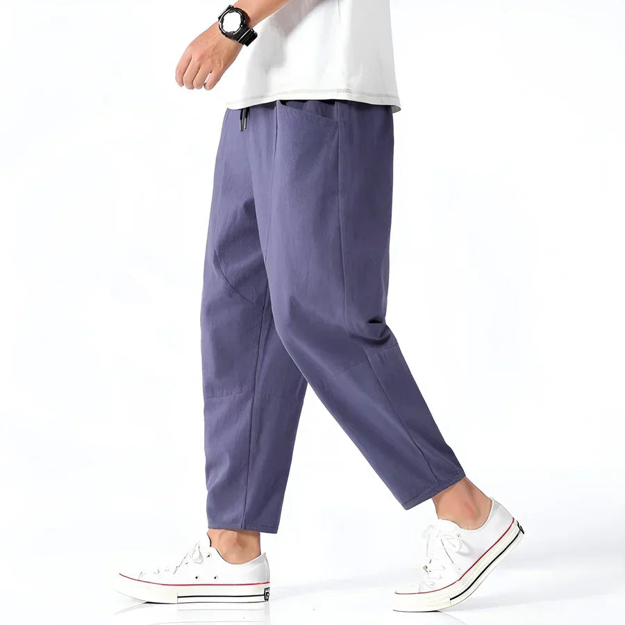 Man wearing casual purple tapered pants from Rovelli, white sneakers, and white shirt