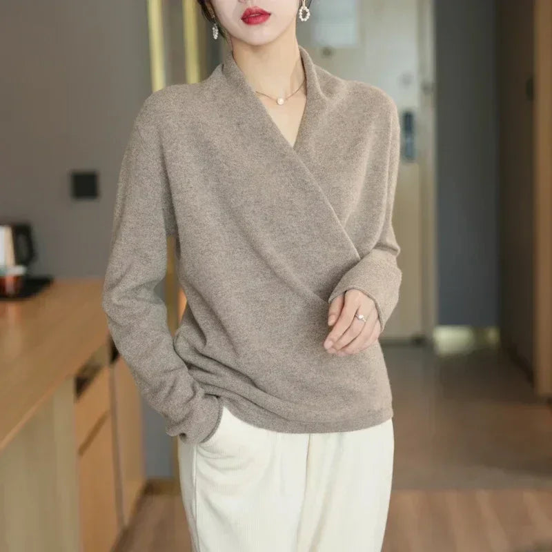Woman wearing a beige Rovelli wrap sweater and white pants in a modern indoor setting