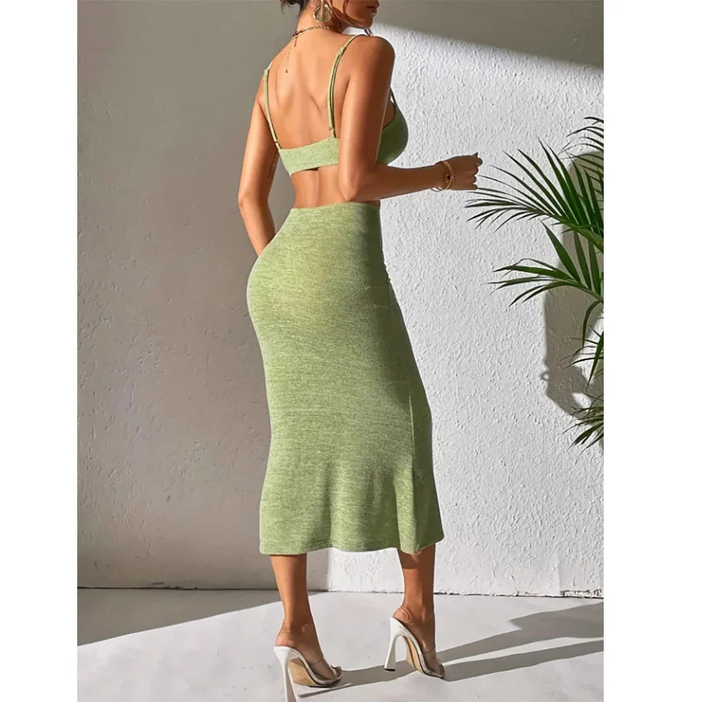 Woman in green sleeveless knit dress and heels posing by white wall, Rovelli fashion